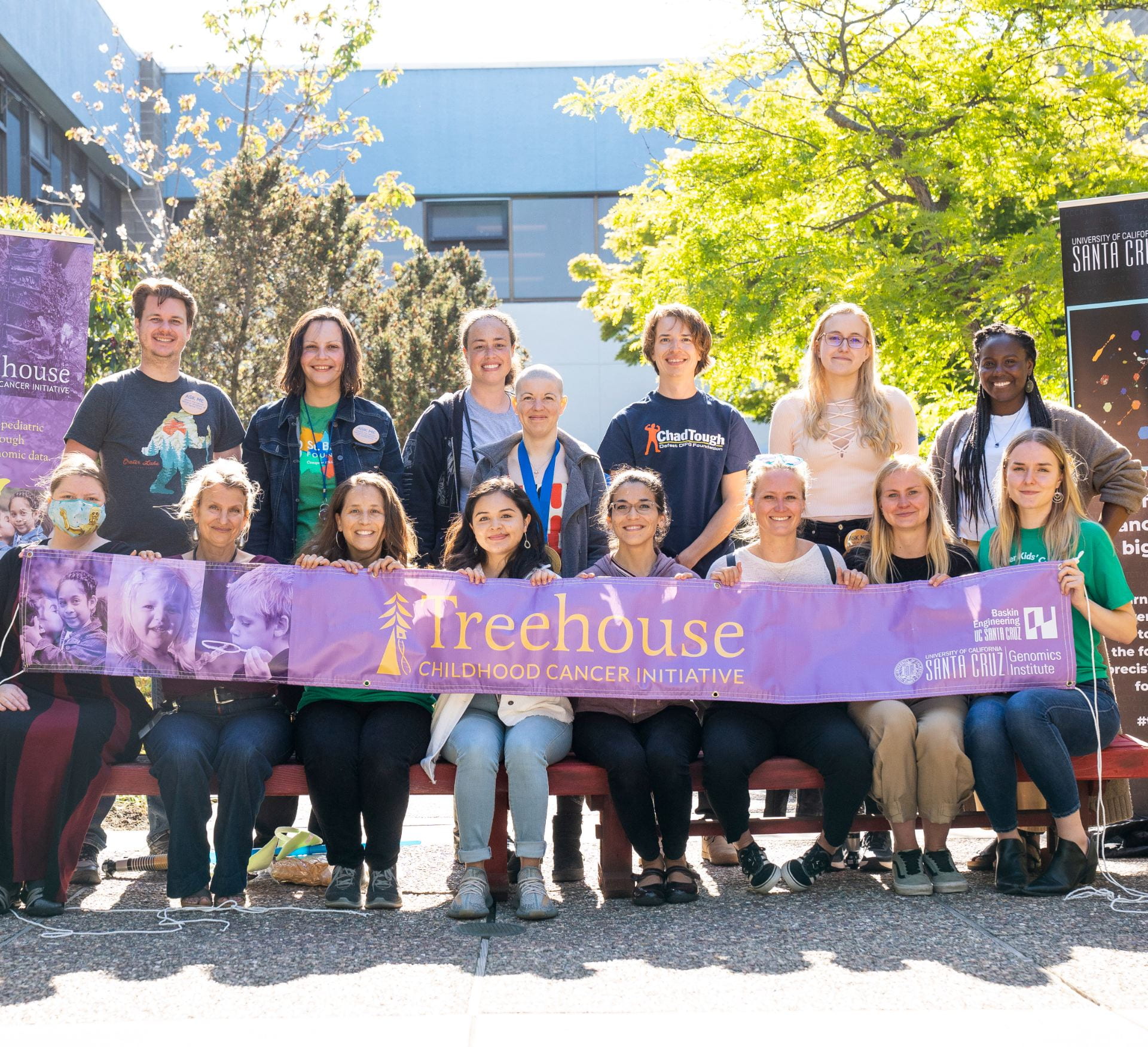 A group photo of a team holding a "Treehouse Childhood Cancer Initiative" Banner