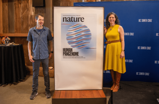 Karen Miga and Benedict Paten posing next to  Human Pangenenome Reference Consortium banner 