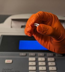 orange glove holding a optofluidic chip